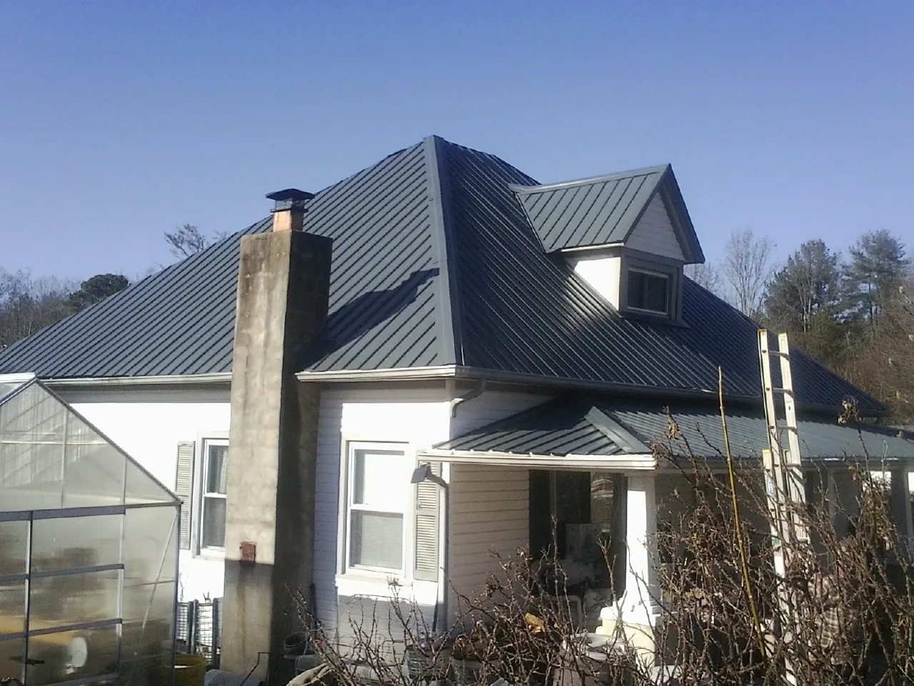 Dark blue standing seam metal roof on a white farmhouse with dormer — Slate & Tile Roof Repair by Roofing Brothers in Donnelsville