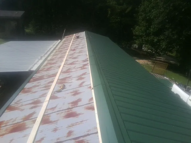 Old rusted panels beside newly installed green metal roofing — Wind Damage Roof Repair by Roofing Brothers in Donnelsville