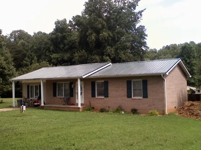 Gray metal roof on a brick ranch house with a side carport in Donnelsville