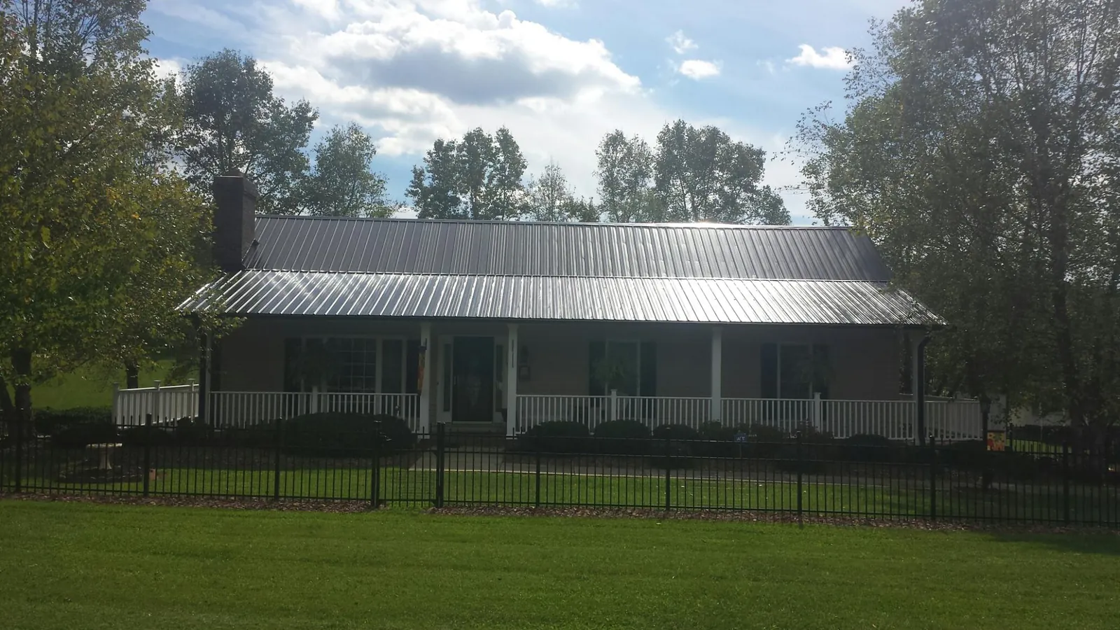Gray metal roof on a brick ranch with a full width front porch — Gutter Guard Installation work by our crew in Donnelsville