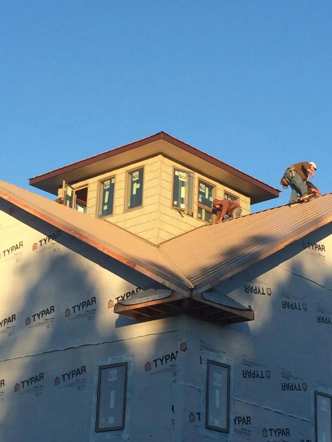Roofers working around a rooftop cupola on a new metal roof at sunset — Roof Waterproofing in Donnelsville by Roofing Brothers